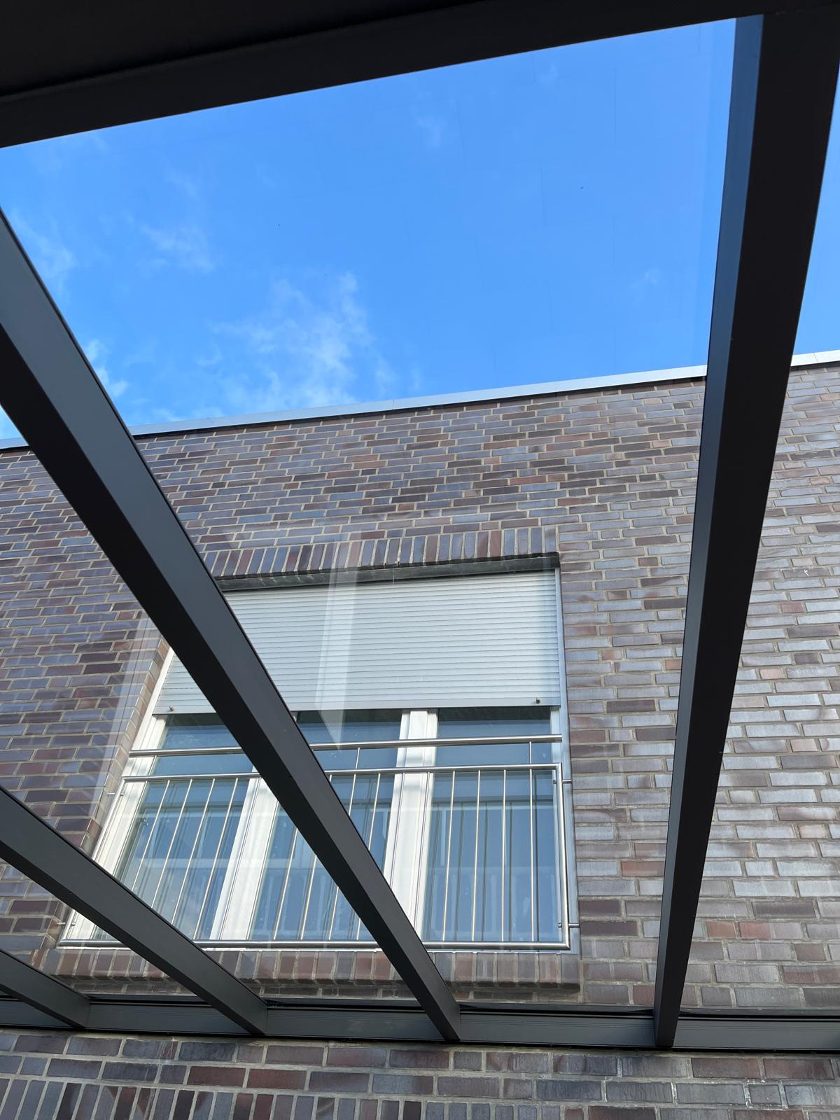Saubere Terrassenueberdachung aus Metall und Glas mit klarer Durchsicht nach der Reinigung