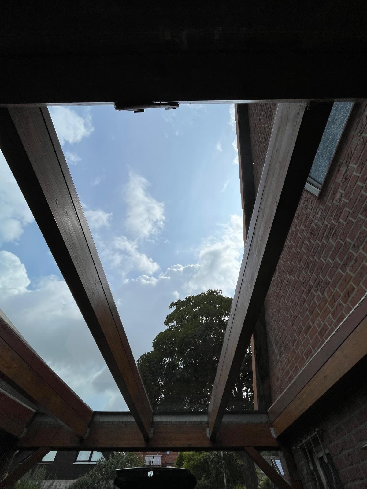 Saubere Terrassenueberdachung aus Holz und Glas mit freiem Blick zum Himmel nach der Reinigung