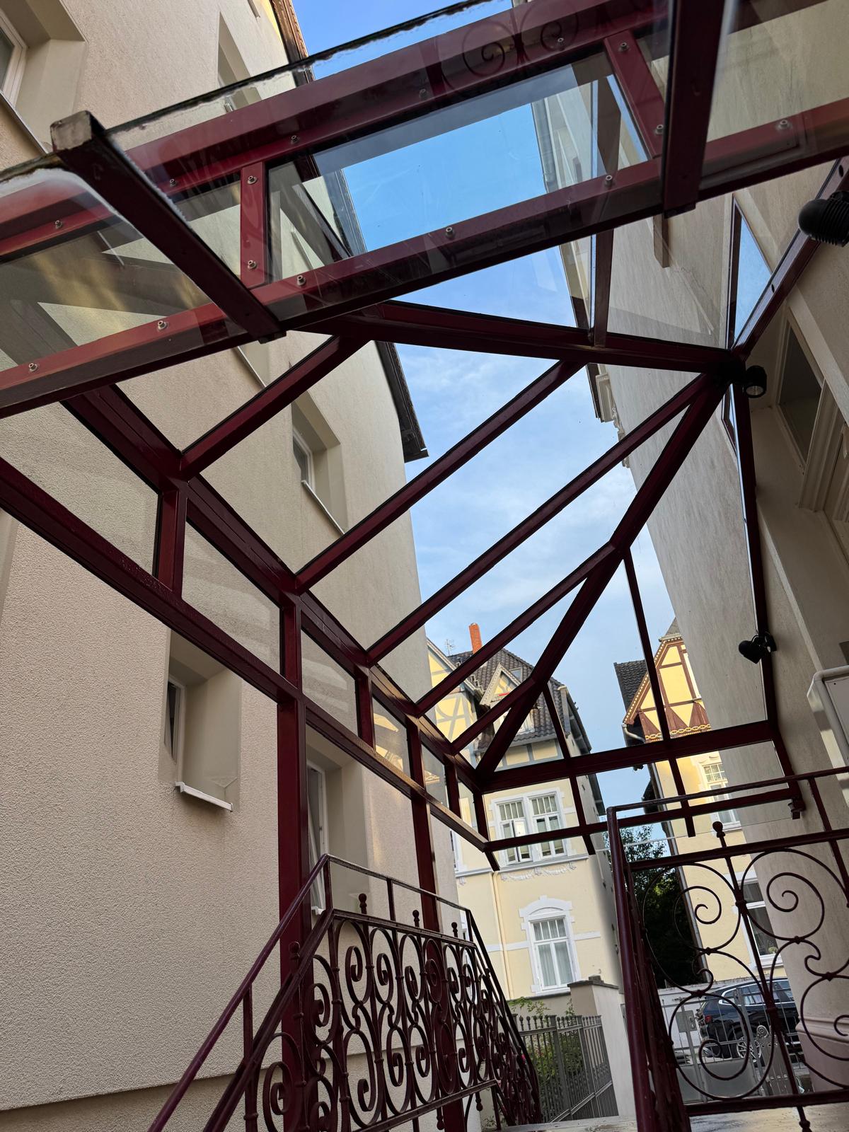 Sauberes Glasvordach mit roter Metallkonstruktion nach der Reinigung